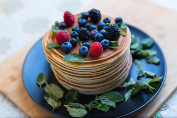 Stack of pancakes. Pancakes with berries. Raspberries and blueberries. Classic Russian dessert. The holiday of Maslenitsa.