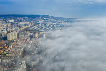 Obraz premium Fog clouds coming over the city from sea, aerial landscape from a drone. View from above.