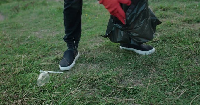 Unrecognizable man collects the plastic lied around the nature