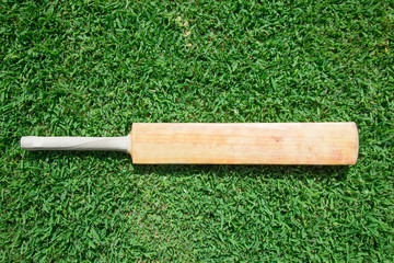 Wooden cricket bat on green grass