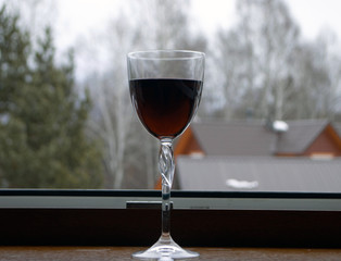  a glass of red wine stands on a windowsill