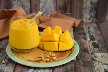 Mango Lassi, Indian popular summer drink served in glass garnish with saffron