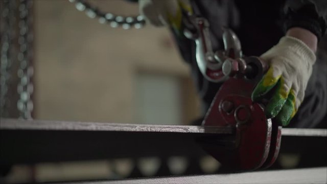 workers adjusting a big pulley hook in a factory. A worker hooks a metal sheet to a crane. Crane chain and hook at an industrial plant. hooks for lifting steel.