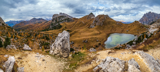 Overcast morning autumn alpine Dolomites mountain scene. Peaceful Valparola Path and Lake view, Belluno, Italy. Picturesque traveling, seasonal, and nature beauty concept scene.