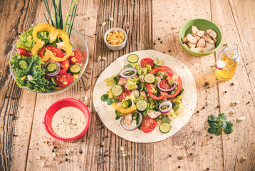 Delicious tortilla wraps on wooden table with vegetable