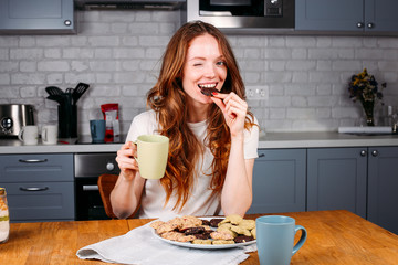 Woman eating cookie and drinking milk.