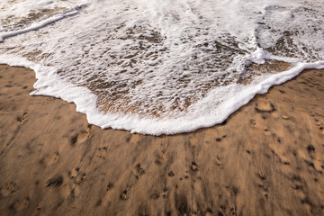 Swirl pattern of a wave rolling onto beach