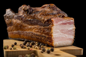 A delicious smoked piece of bacon on a chopping board. A piece of smoked meat from a pig in the kitchen.
