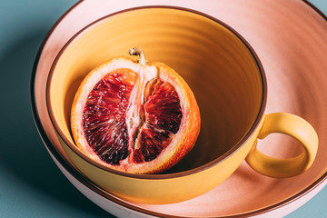 Fresh cut blood orange in yellow bowl, stacked on pink plate