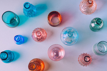 Overhead shot of various colored glasses brightly lit showing reflections and shadows