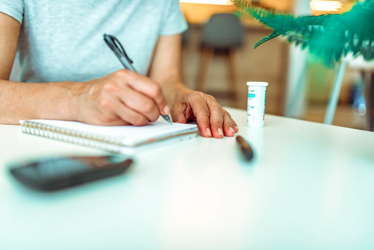 Close up of woman hands holding Glucose meter and use pen to write schedule check blood sugar level to planner notbook with lancet. Use as Medicine, diabetes, glycemia, health care and people concept.