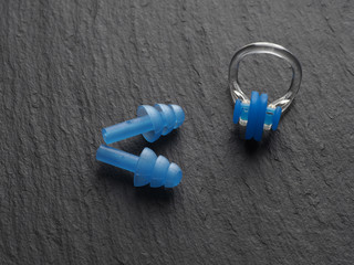 Nose clip and ear plugs for swimming pool on a gray background. Sport equipment. Set of earplugs...