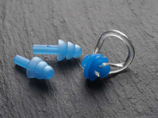 Nose clip and ear plugs for swimming pool on a gray background. Sport equipment. Set of earplugs...