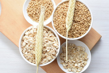 Oat grains and flakes accompanied by wheat ears in containers for display