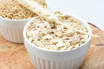 Oat grains and flakes accompanied by wheat ears in containers for display