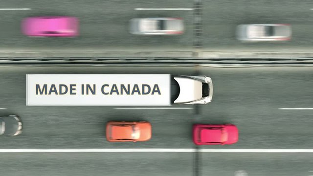 Aerial overhead view of semi-trailer trucks with MADE IN CANADA text driving along the highway. Canadian business related loopable 3D animation