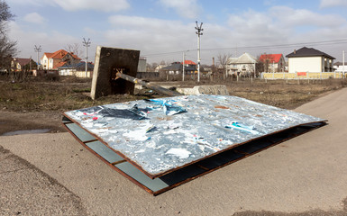 A street billboard is torn down by a strong wind on a stormy day during a hurricane. A strong gusty hurricane wind turned the billboard onto a car road