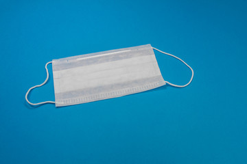 Medical mask of blue color for protection against flu and other diseases isolated on blue background. 3-ply surgical mask to cover the mouth and nose. Healthcarand medical concept.