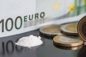 Concept of a drug deal and cheap deadly dangerous drugs. Euro bills, coins and cocaine narcotic...