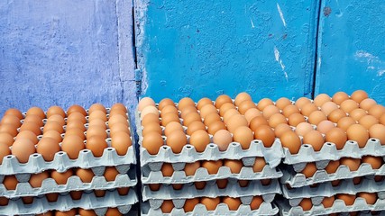 Stacks of brown eggs along blue wall outdoors Morocco