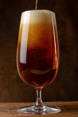 Beer pouring into a glass on the rust background