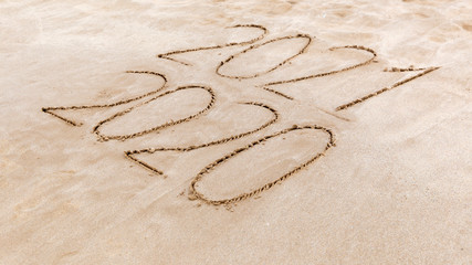 Handwritten inscription of years calendar 2020, 2021 on a sandy sea beach on a summer sunny day. Happy New Year concept.