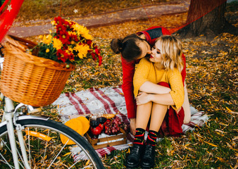 Beautiful picnic of young couple in the park. Yellow and red colors. The moment of the kiss