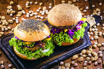 homemade vegan burger, with vegetables and various grains, on rustic wooden background. Healthy and vegetarian life concept. meatless snack, based on soy, chickpeas, corn and proteins.