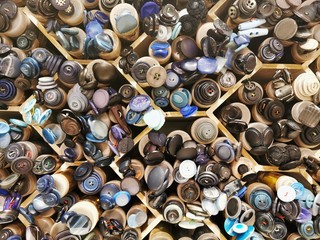 Various buttons for clothes in plastic containers on shelves of sewing store. 