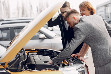Couple in a car salon. Family buying the car. Elegant woman with her husband. Assistant with a clients
