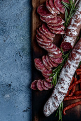 Fuet, a traditional Spanish sausage with rosemary. Slice sausages. Rosemary. Top view. Free space for your text.