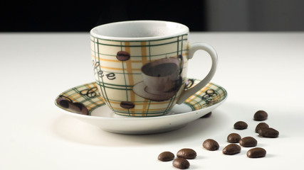 A Cup of hot coffee with scattered grains on a white table