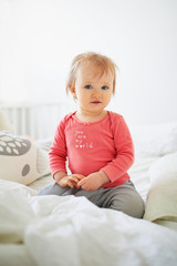 Fototapeta premium Adorable toddler girl sitting on bed