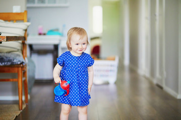 Fototapeta premium Baby girl in blue dress putting her water bottle on the table