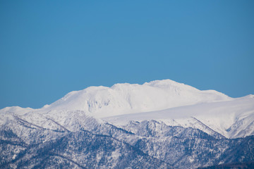 Fototapeta na wymiar 雪山の山頂と青空　十勝岳連峰