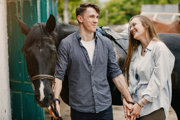 Fototapeta premium Couple on a ranch. Pair standing with a horse. Girl with her boyfriend