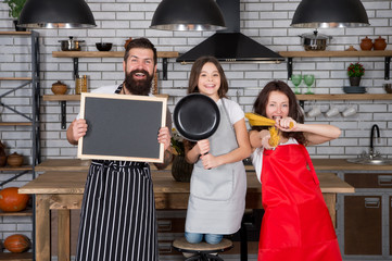 Best cooking team. Mom dad and daughter aprons in kitchen. Lunch time. Family having fun cooking together. Teach kid cooking food. Cooking together. Recipe copy space. Family restaurant concept