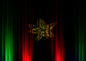 Black backdrop with green and red lights with a yellow star in the middle in a city theater