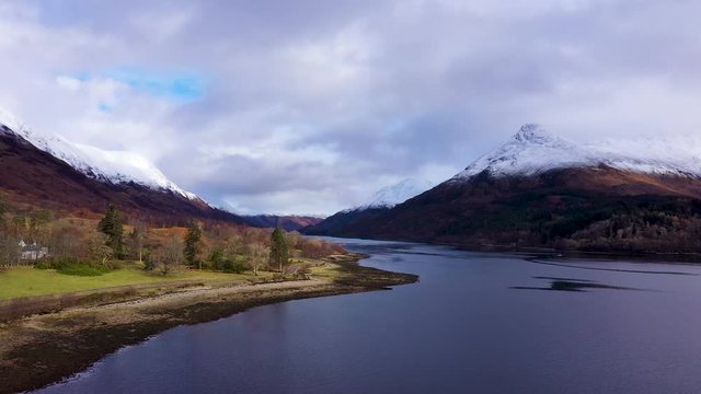 aerial drone footage of winter in glencoe and and loch leven in the argyll region of the highlands of scotland showing clear bright white snow on the mountains of glencoe and the surrounding region