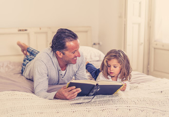 Father and cute young daughter reading a book together