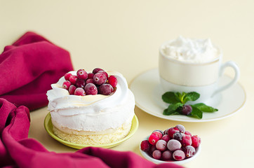 dessert with meringue, whipped cream, red berries cranberries, cappuccino coffee with lush foam on yellow background with copy space, soft focus