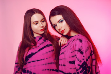 2 girls in the same things with bright makeup. Brunette girls, sisters, girlfriends, twins. Women's power, March 8, Women's Day. Clothing store for teens. Pink color in clothes