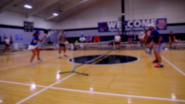 SOFT FOCUS SHOT OF A FOURSOME PLAYING PICKLEBALL.  ALL PLAYERS UNRECOGNIZABLE.  SLOW MOTION FULL HD AT 180 FPS.