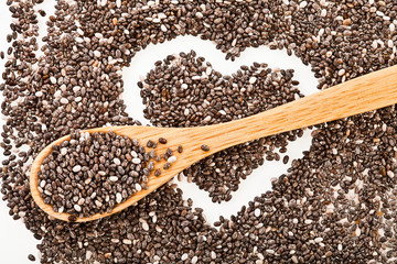 Background of chia seeds with heart shape and wooden spoon.