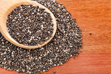 Chia seeds in a wooden spoon on a wooden table.
