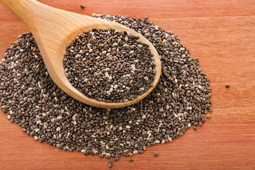 Chia seeds in a wooden spoon on a wooden table.