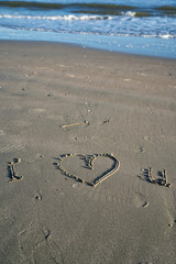 Fototapeta na wymiar ich liebe dich! Ein Herz in Sand gemalt, am Strand in Florida - während goldener Stunde, Meer und Wellen im Hintergrund