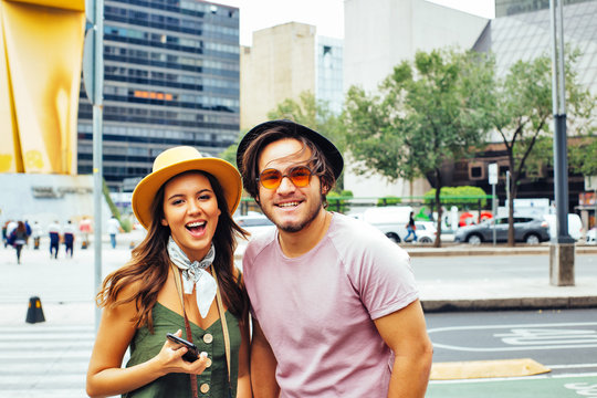 Portrait of happy young couple of trendy tourists with hats smiling at the camera in Mexico City