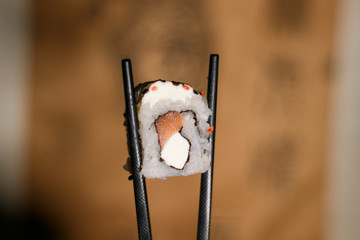 Rollo de Sushi sostenido por palillos chinos