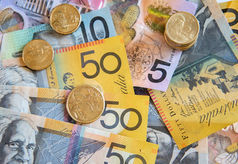 Australian notes and coins spilled out and stacked on a table.